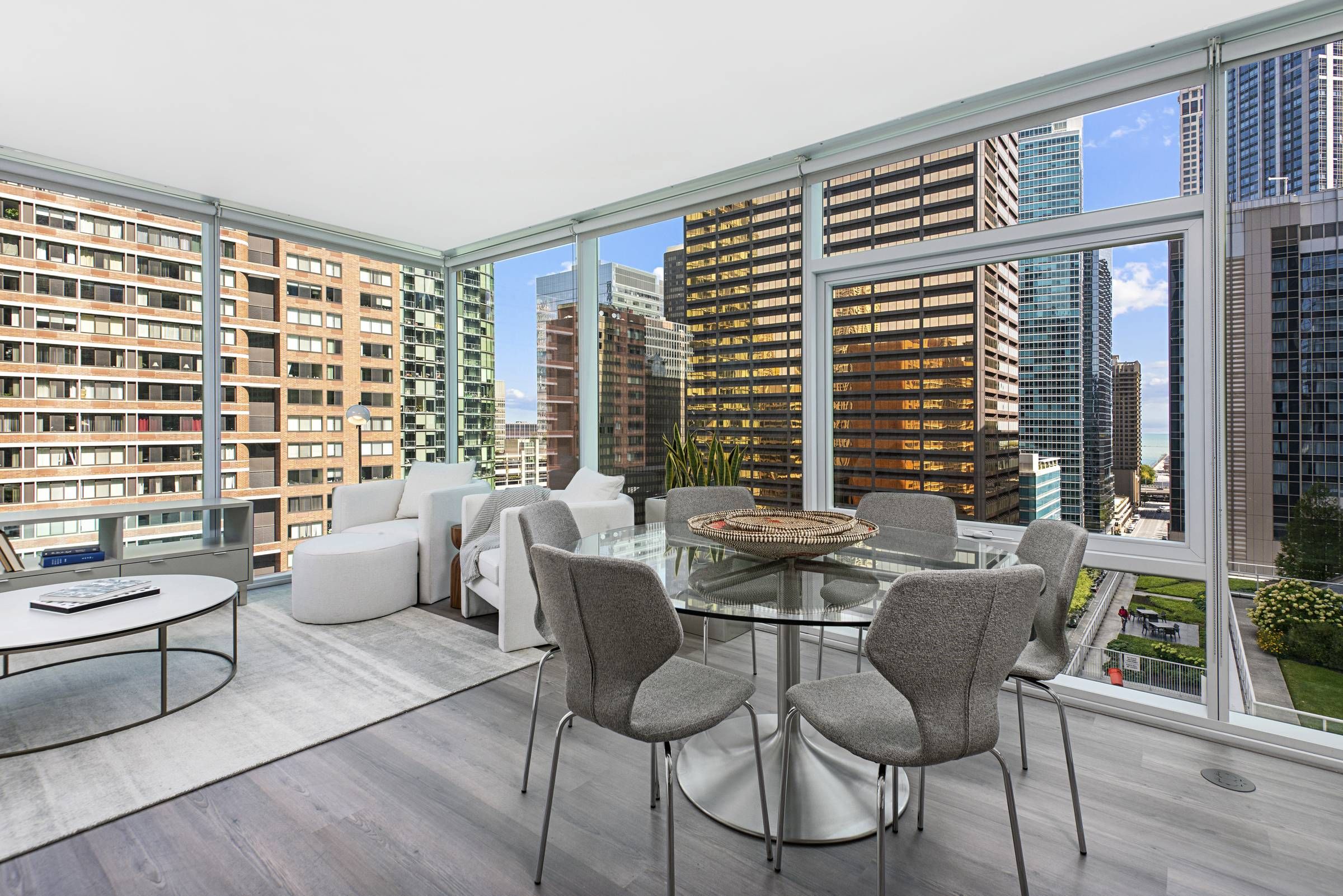 Optima Signature in Downtown Chicago with Modern apartment with large windows, city views, gray dining chairs, glass table, and cozy seating area.