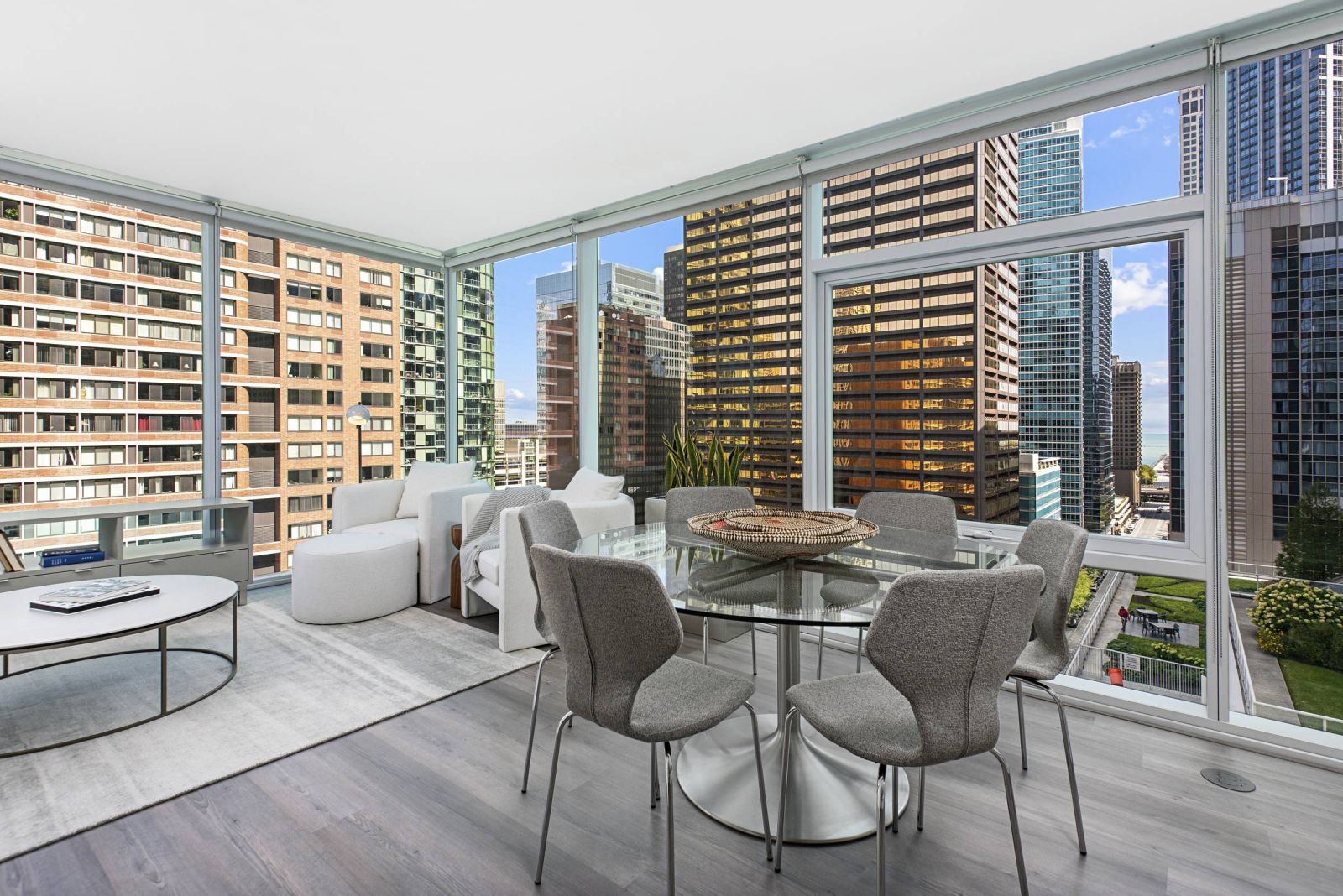 Optima Signature in Downtown Chicago with Modern apartment with large windows, city views, gray dining chairs, glass table, and cozy seating area.