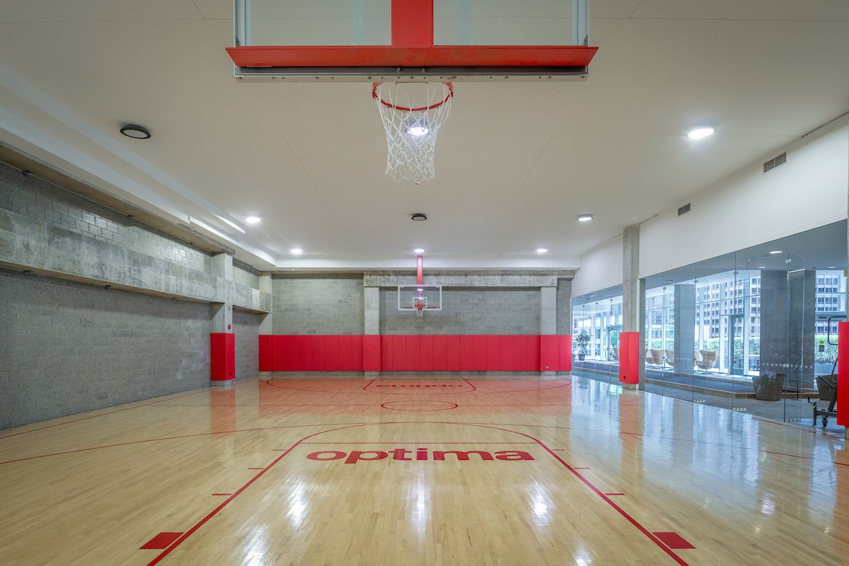 Optima Signature in Downtown Chicago with Indoor basketball court with wooden flooring, red markings, and glass walls on one side displaying city buildings.