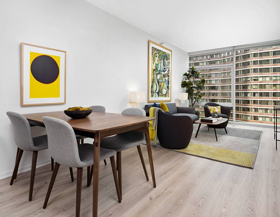 Optima Signature in Downtown Chicago with Modern living and dining area with minimalist furniture, bright artwork, and large window overlooking buildings.