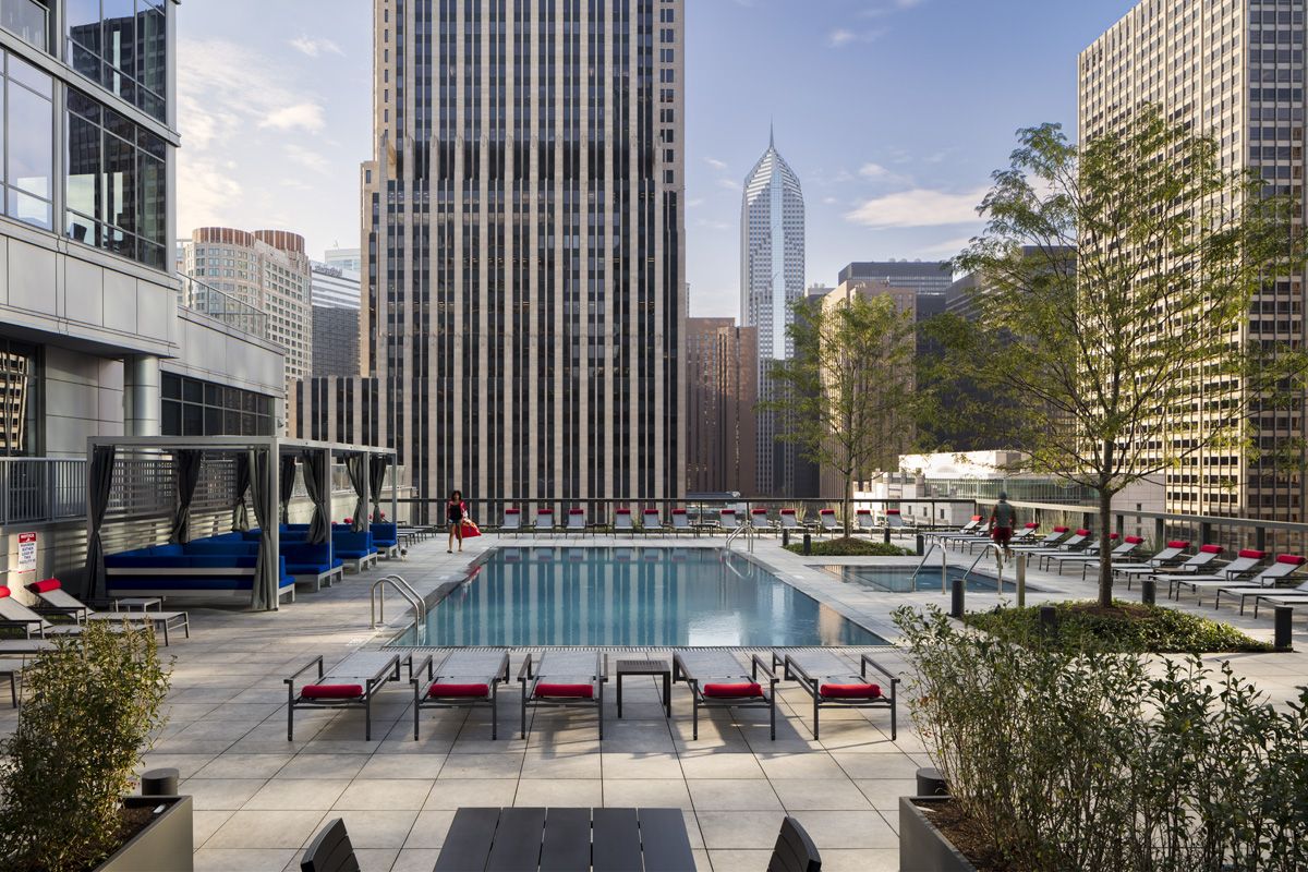 Optima Signature in Downtown Chicago with Rooftop pool with lounge chairs and city skyscrapers in the background on a sunny day.