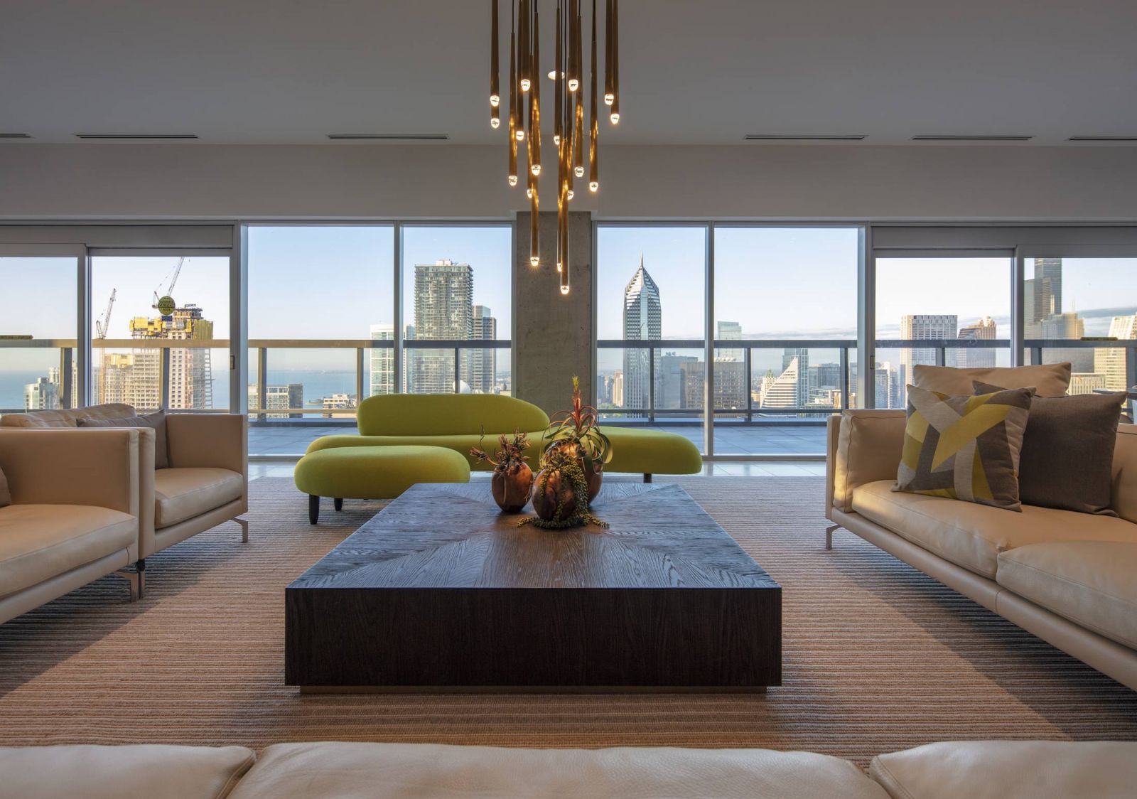 Optima Signature in Downtown Chicago with Modern living room with large windows, city skyline view, neutral sofas, green bench, and a wooden coffee table.