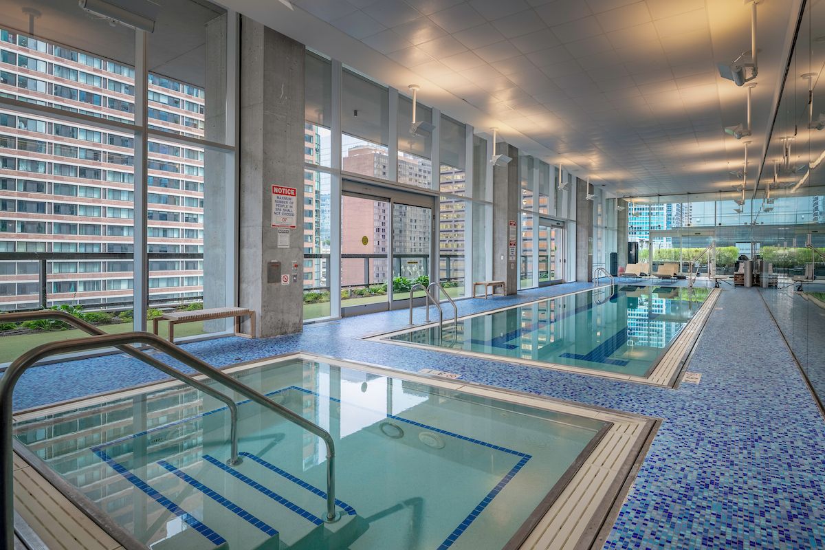 Optima Signature in Downtown Chicago with Indoor pool and hot tub area with large windows overlooking city buildings and greenery.